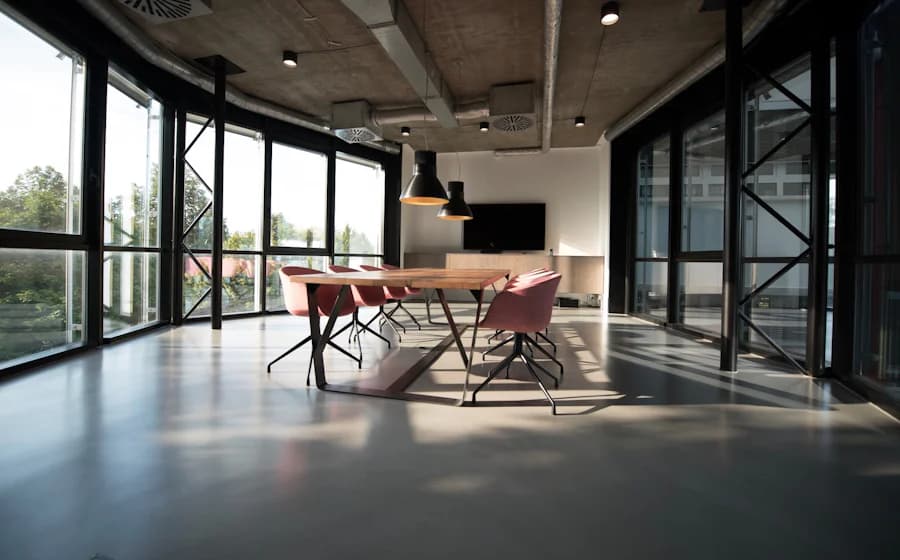 An empty modern meeting room with a long wooden table, pink chairs and floor-to-ceiling windows
